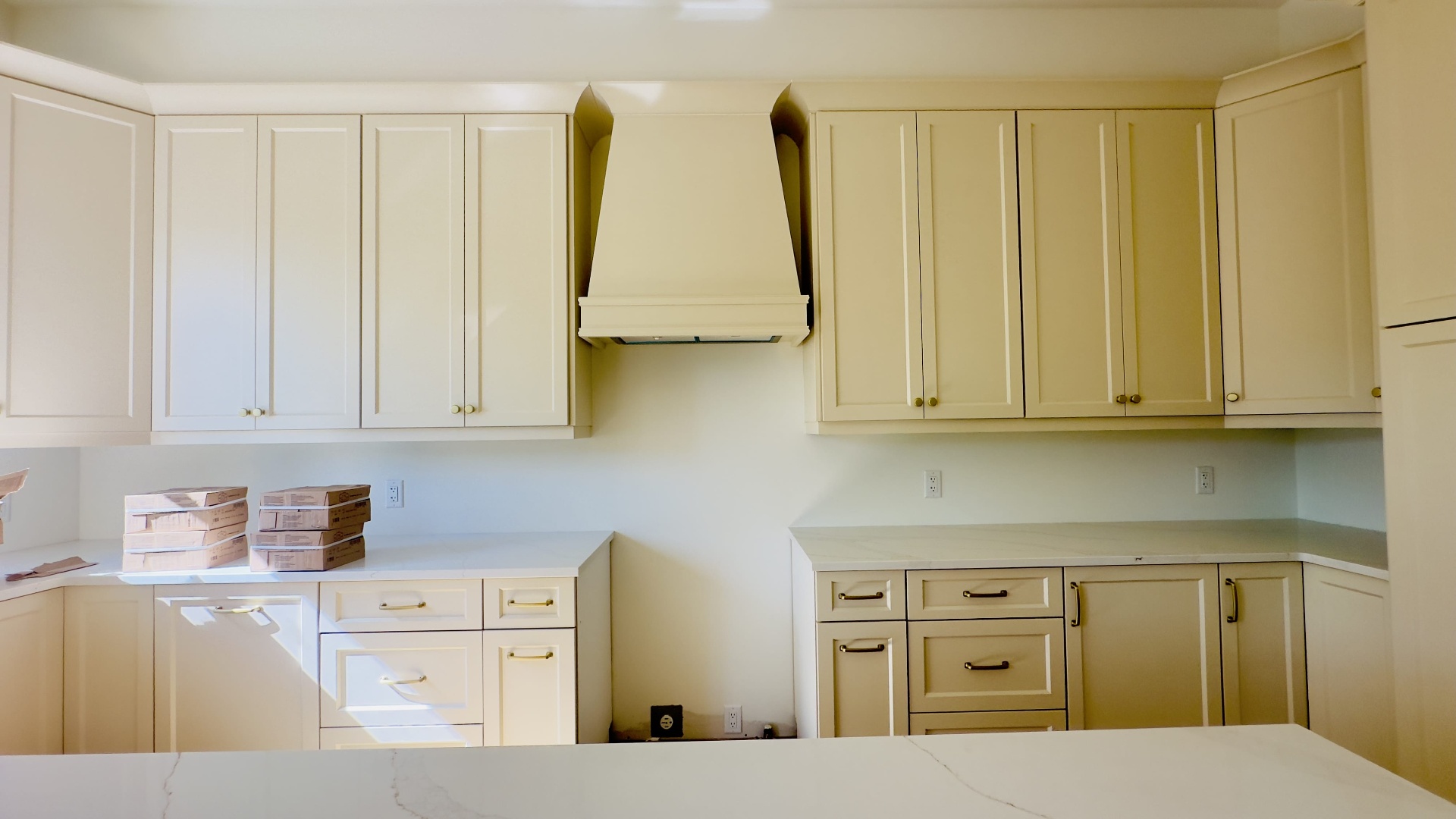 Kitchen renovation with custom hood, cream shaker cabinets and quartz counters in Niagara