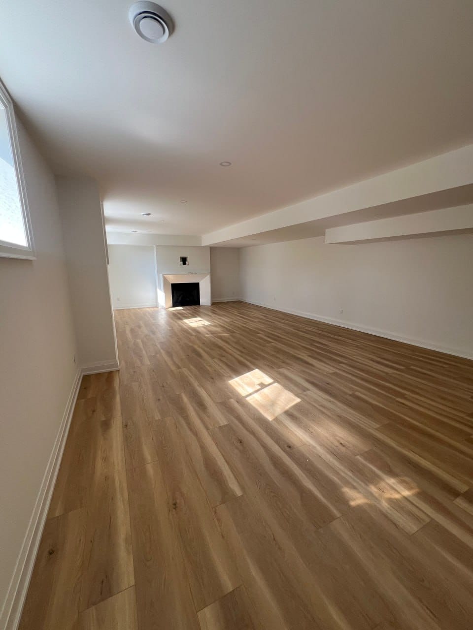 Grimsby interior renovation — finished open basement with wood-look flooring and fireplace