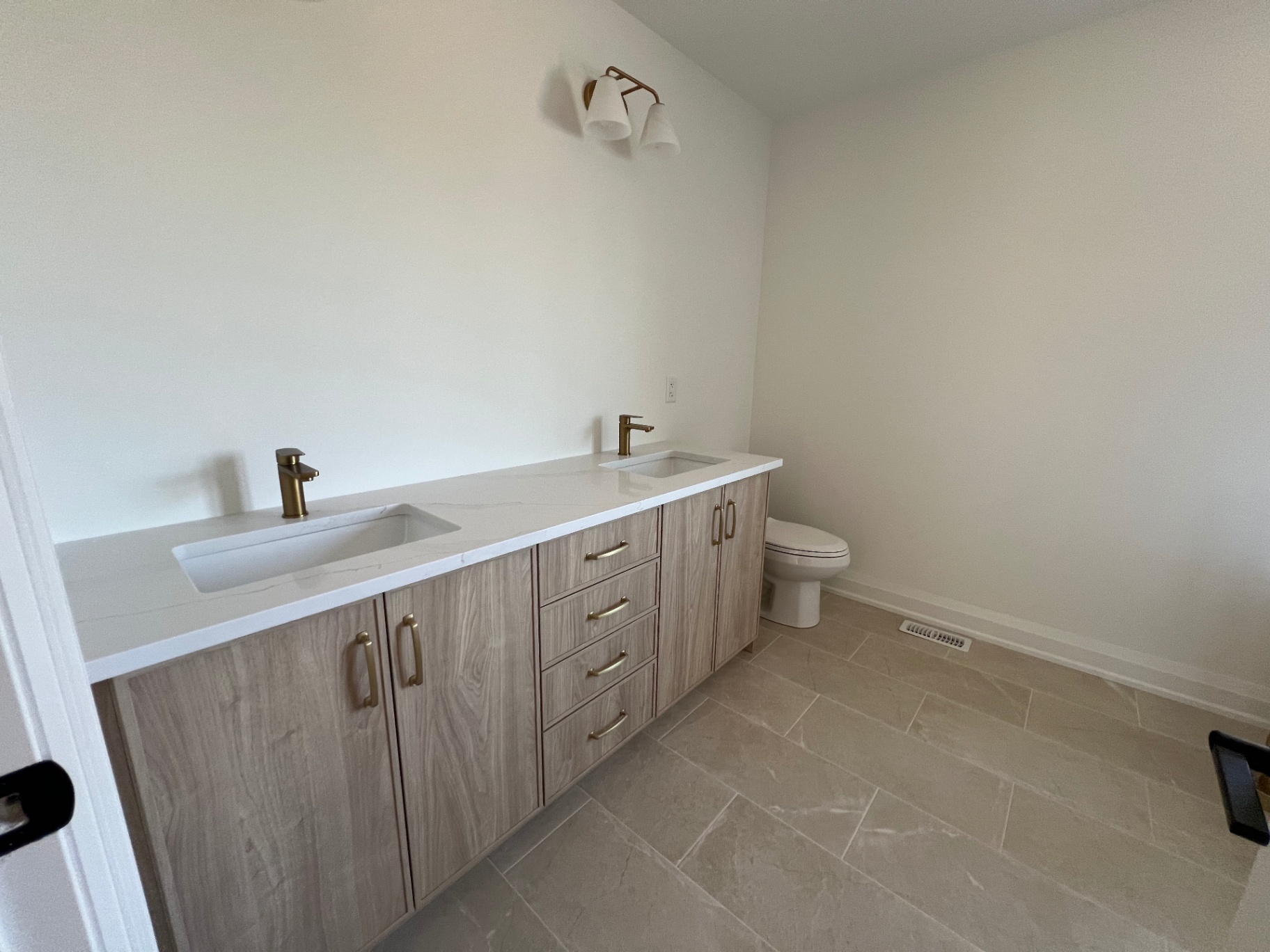 Bathroom renovation with floating double vanity and gold fixtures in Niagara