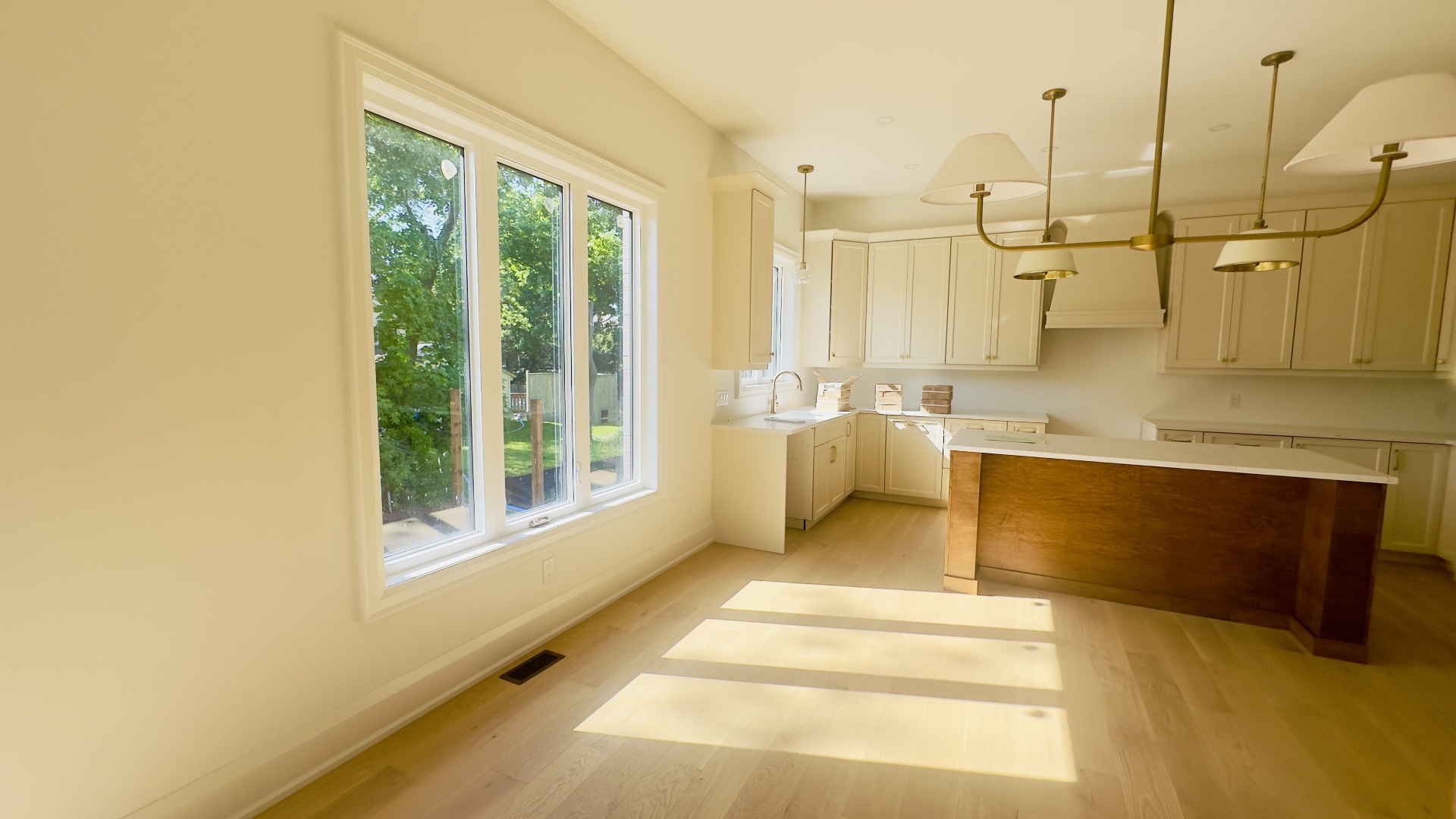 Kitchen renovation with cream cabinets, quartz counters and brass chandelier in Niagara