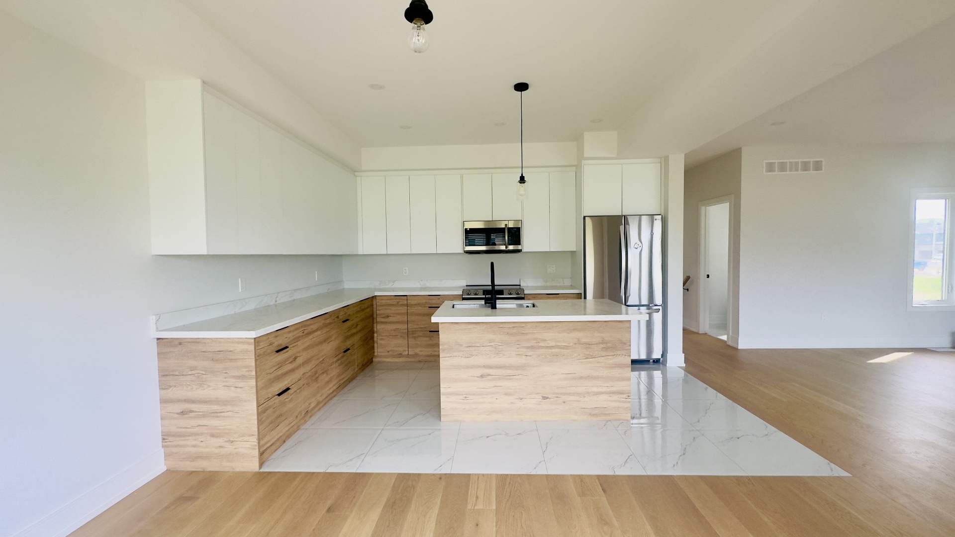 Kitchen renovation with wood cabinets, quartz island and marble tile flooring in Niagara