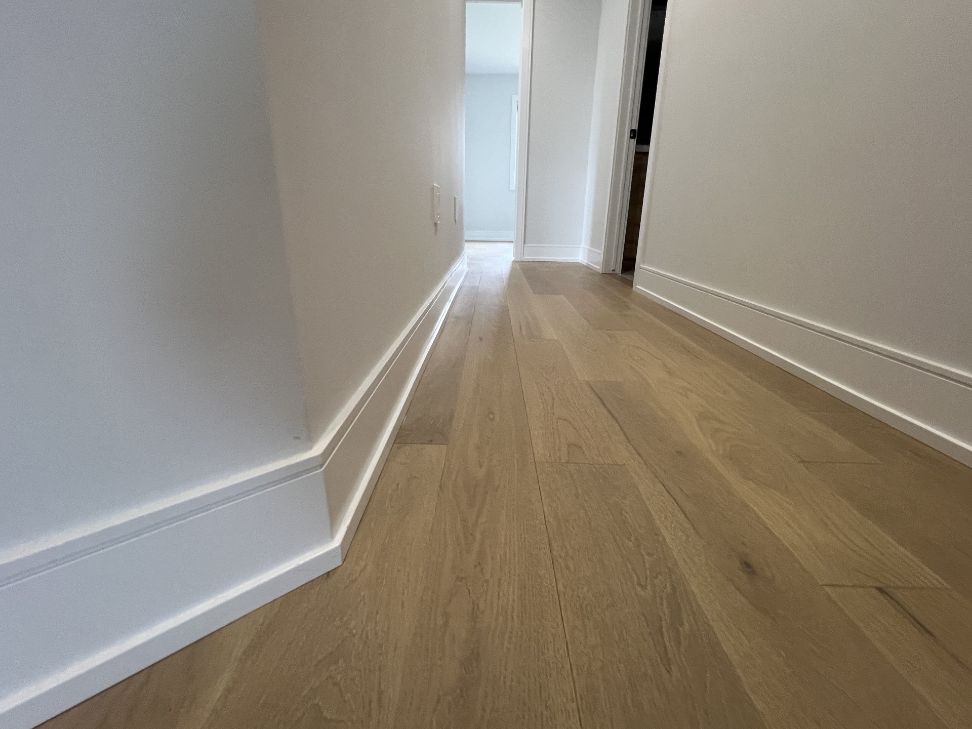 Niagara Falls interior renovation — hallway with wide-plank hardwood flooring and tall painted baseboards