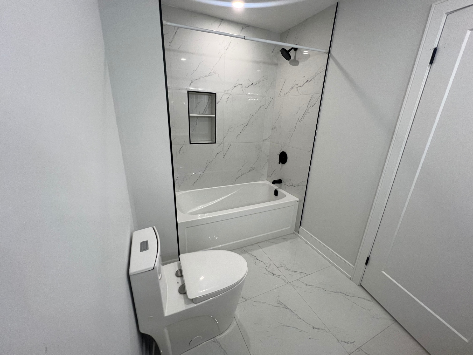 Bathroom renovation with tub-shower combo and marble-look tile in Niagara