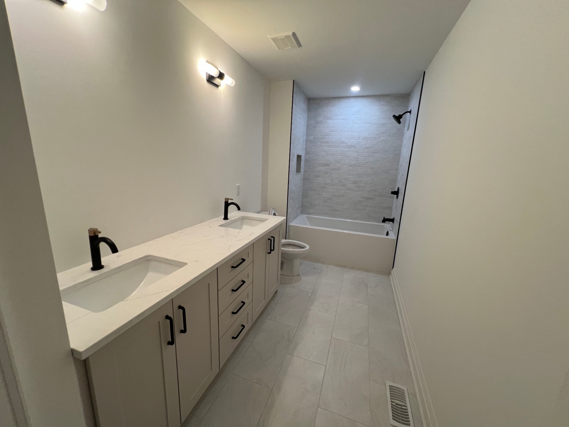 Bathroom renovation with double vanity, tub-shower and tile surround in Niagara