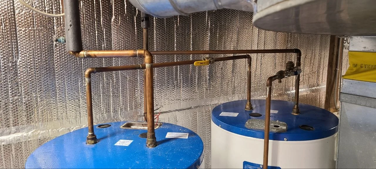 Upper connections and copper pipework above two storage water heaters