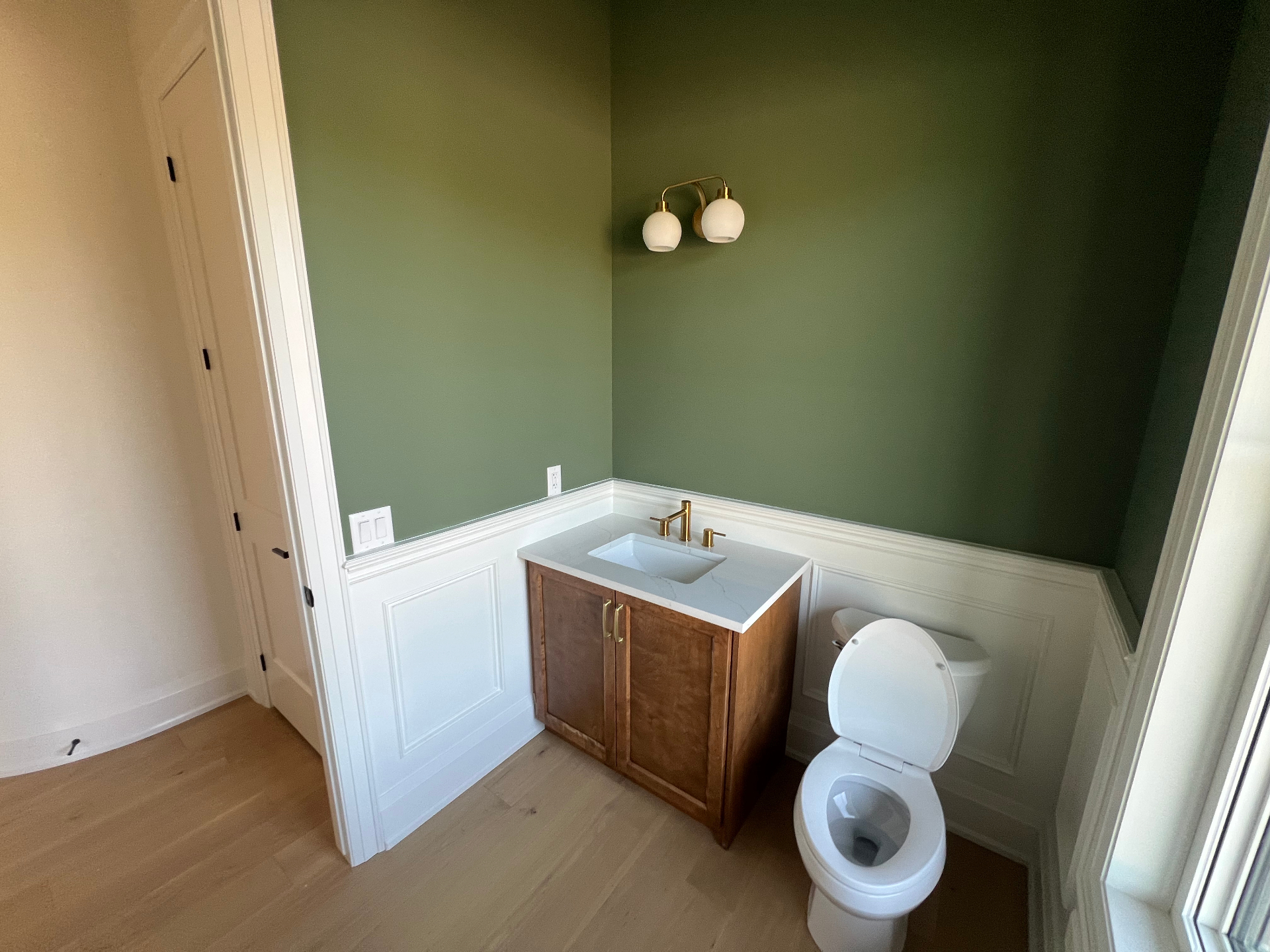 Powder room renovation with green walls, wainscoting and wood vanity in Niagara