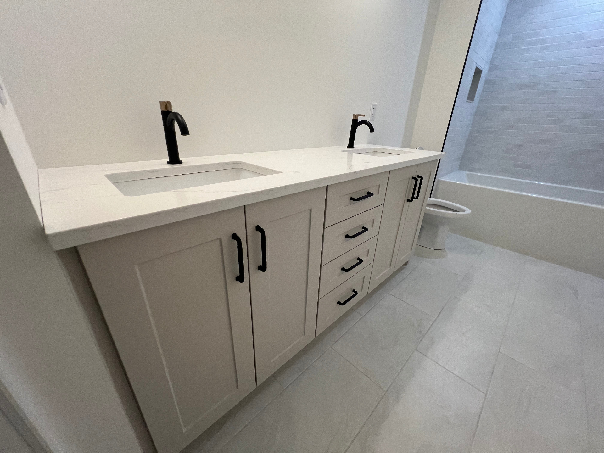 Bathroom renovation with white shaker double vanity and tub area in Niagara