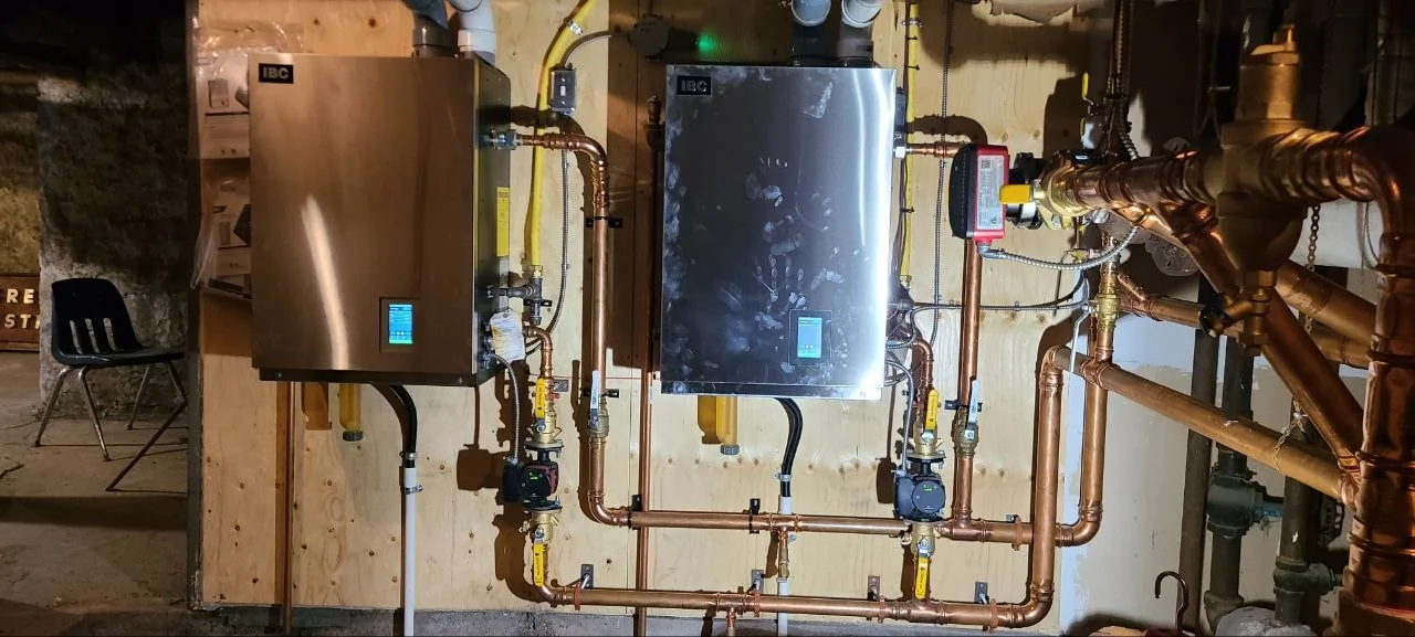 Two wall-mounted IBC gas boilers with copper pipework and circulators
