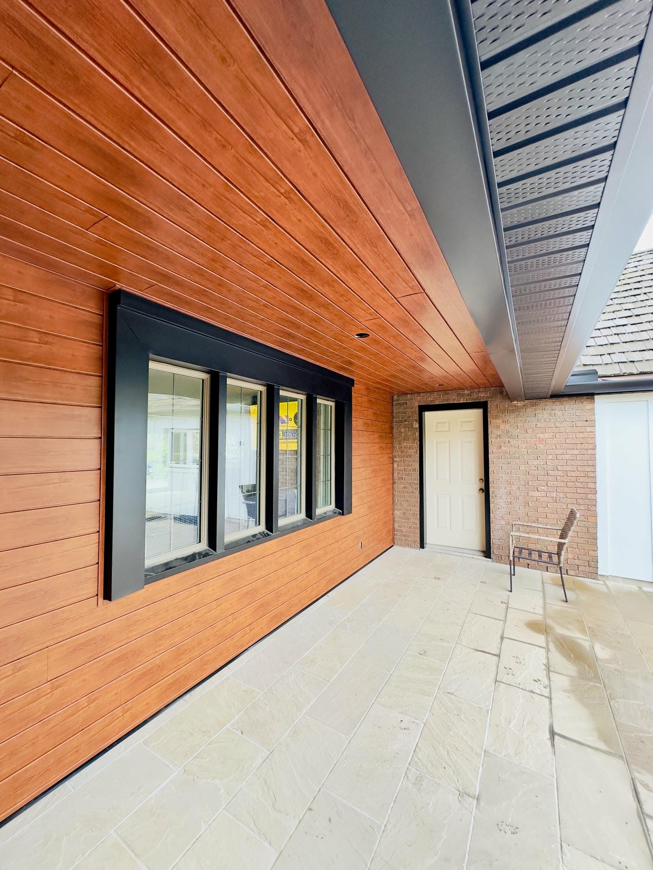 Wood-look aluminum siding with black window trim and soffit detail in Niagara