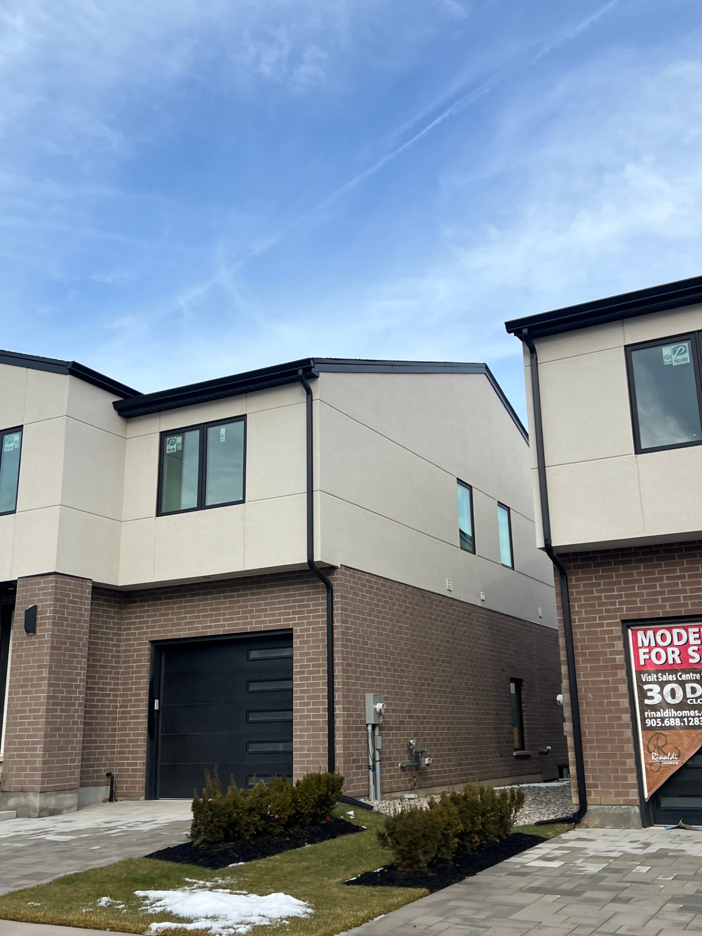 Modern stucco townhome exterior with brick base and clean upper stucco walls
