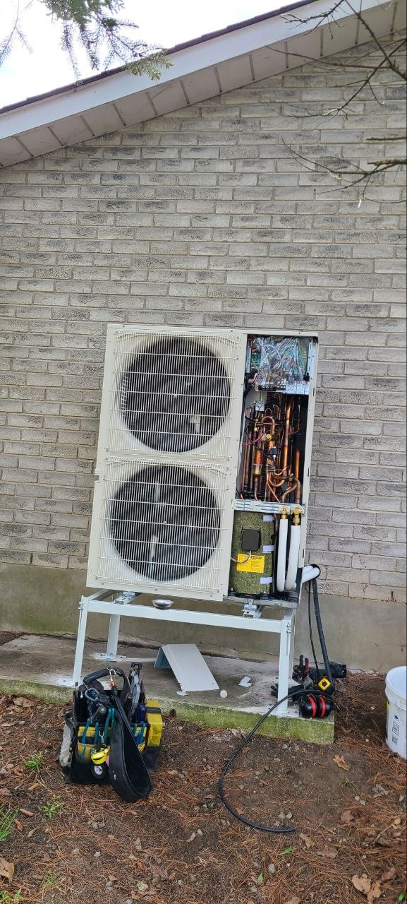 Dual-fan outdoor heat pump with its service panel open during installation