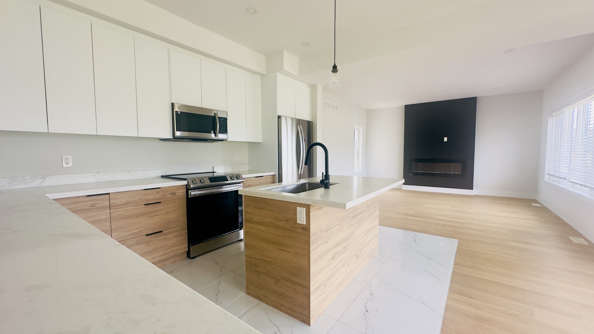Open concept kitchen renovation with wood cabinets, quartz island and fireplace in Niagara