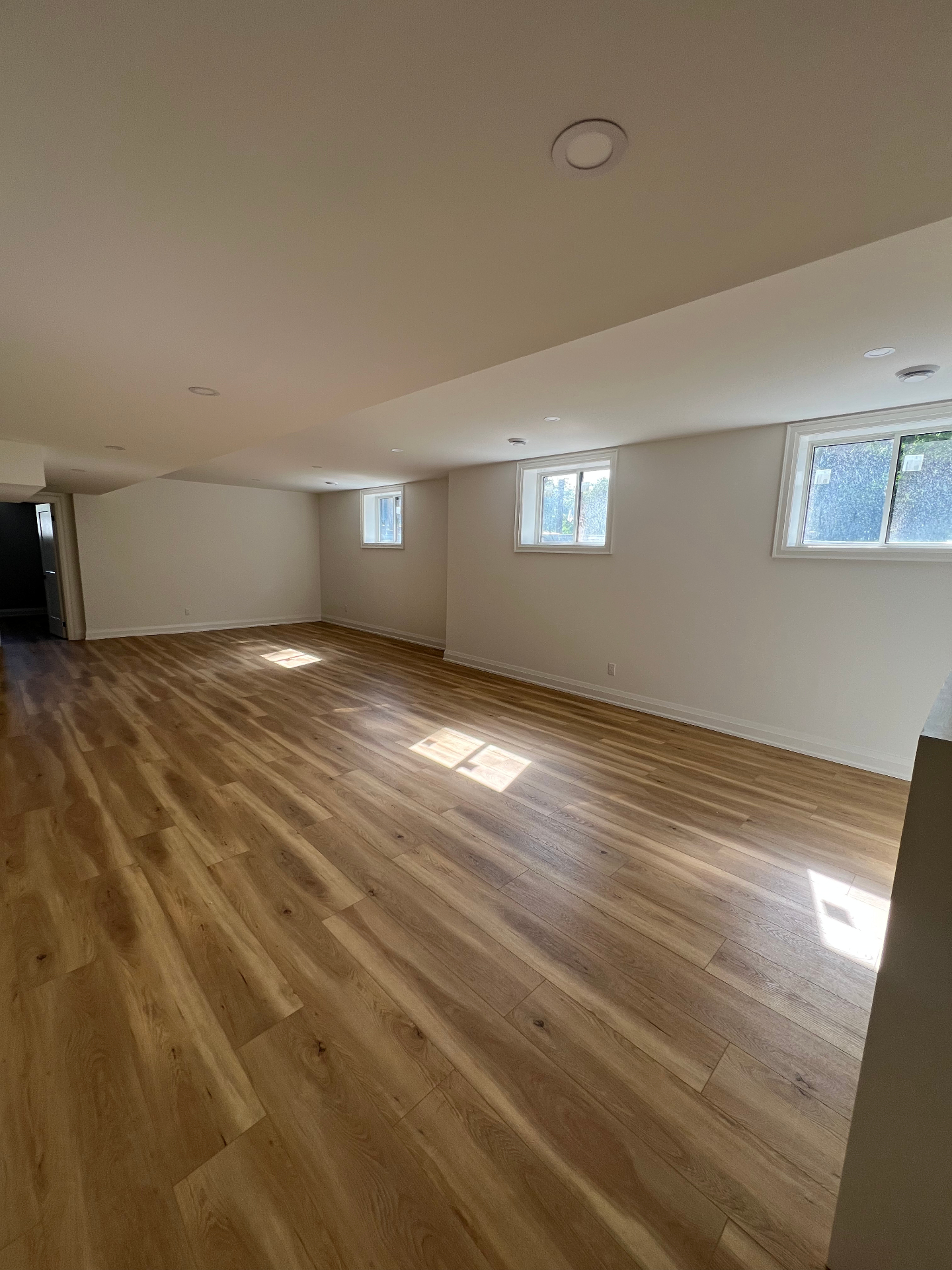Finished basement living space with hardwood flooring and recessed lighting in Niagara