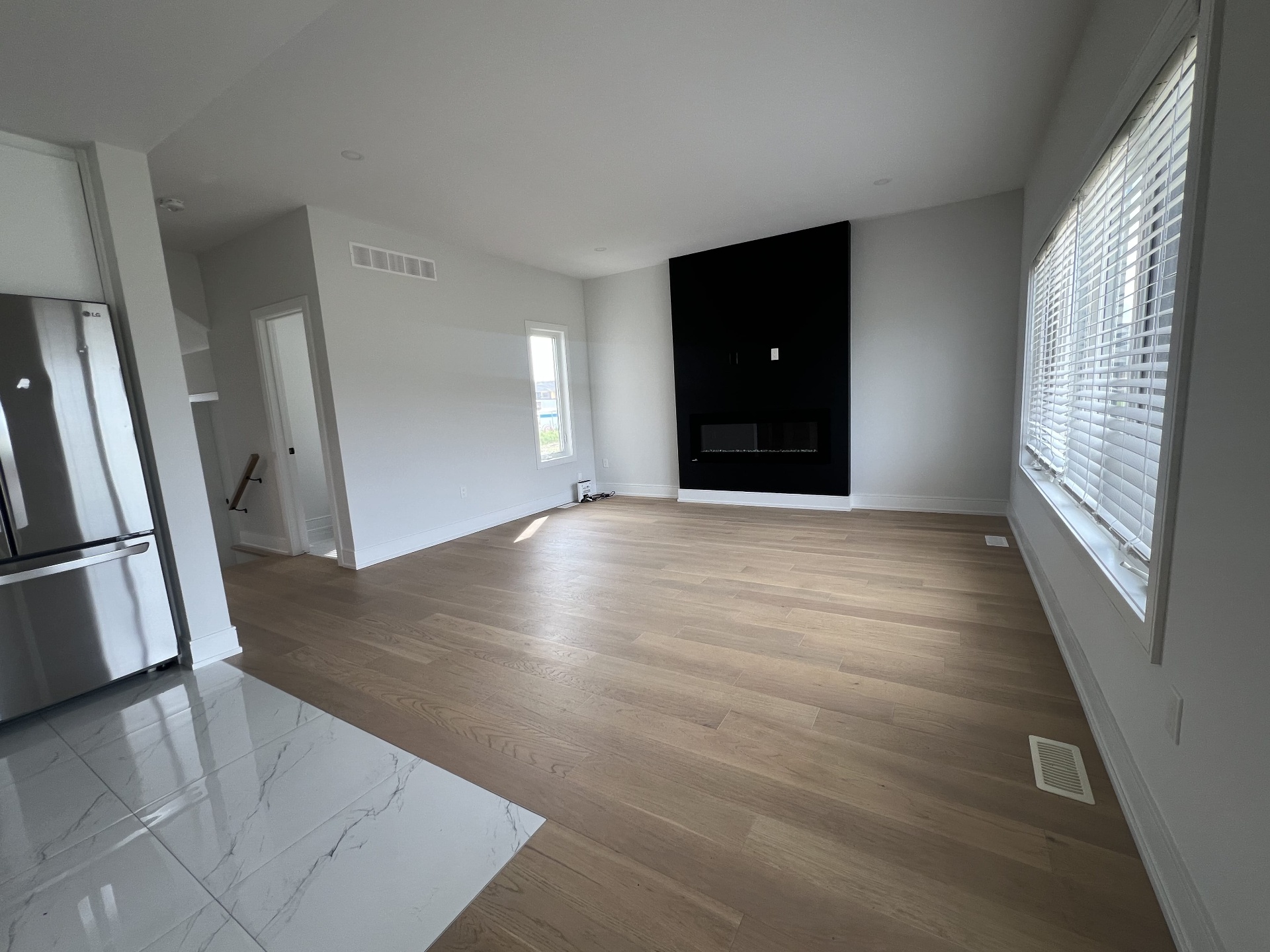Niagara Falls interior renovation — open living room with black feature wall, linear fireplace, and wide-plank hardwood flooring