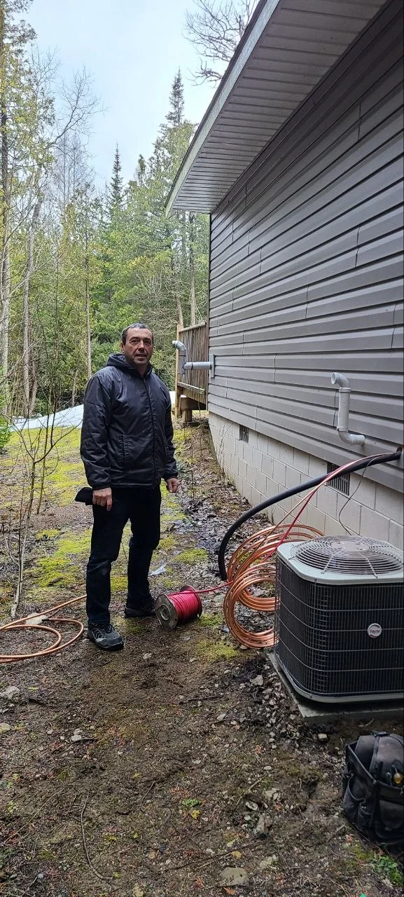 Yuriy, lead HVAC technician, beside outdoor HVAC equipment.