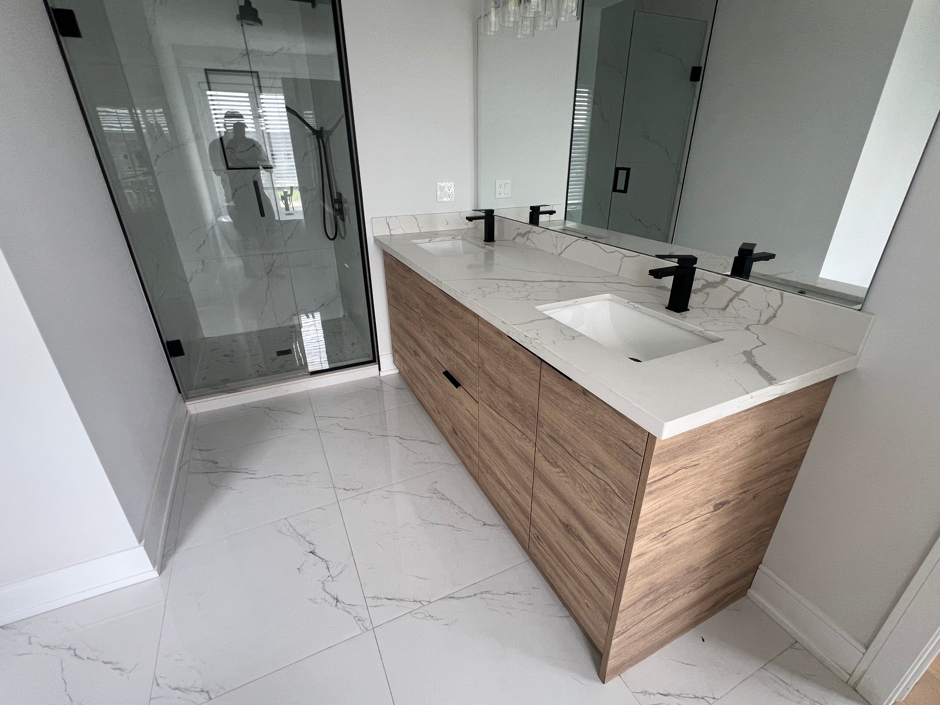 Bathroom renovation with wood double vanity, quartz counter and glass shower in Niagara